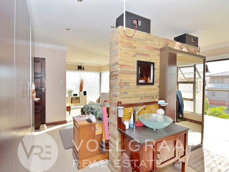 Bedroom featuring a stone-clad partition wall with an integrated vanity and vessel sink, built-in cupboards, and access to an outdoor area.
