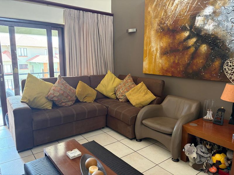 A comfortable living room featuring ceramic floor tiles and a large sliding glass door that provides access to the outdoor area.