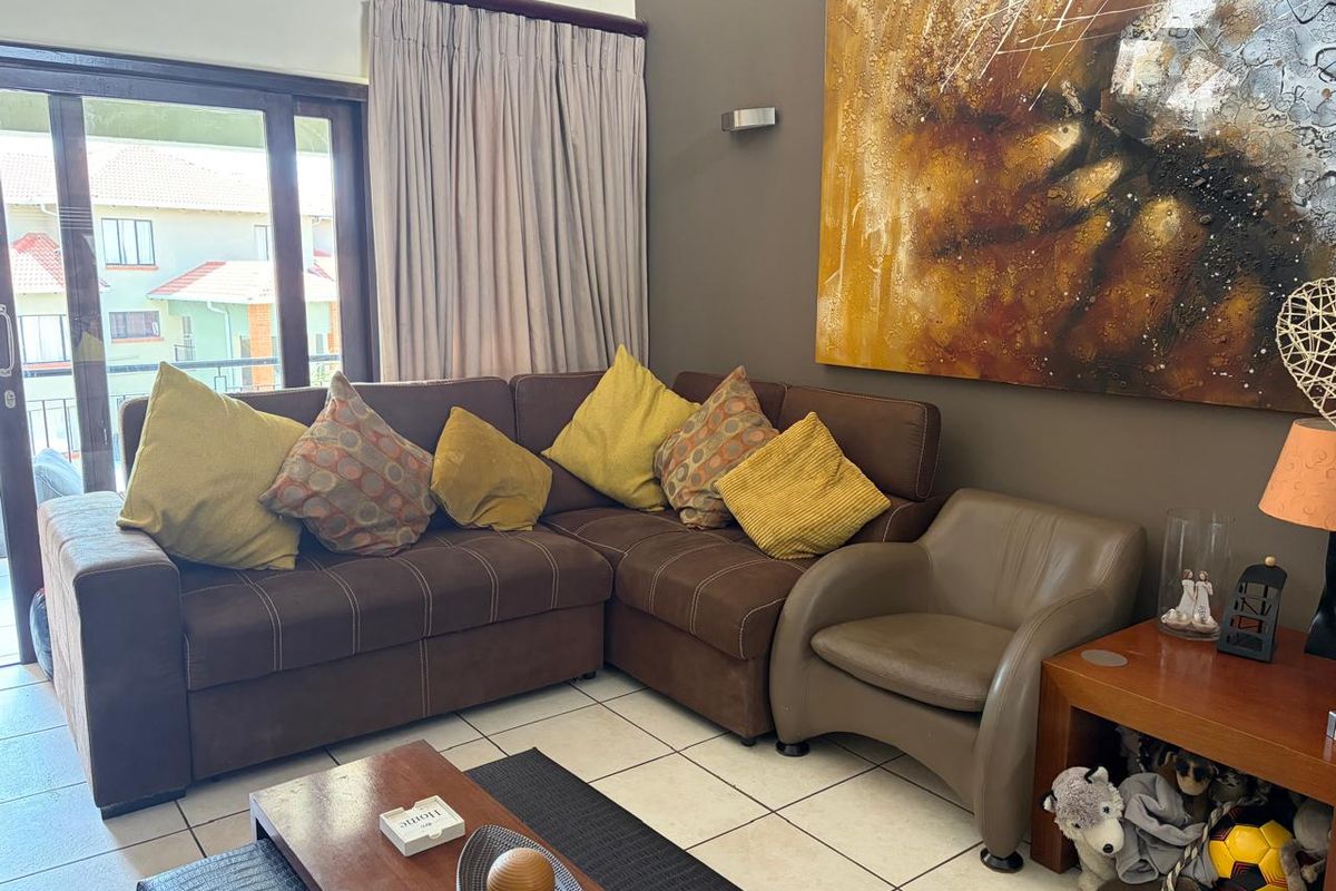 A comfortable living room featuring ceramic floor tiles and a large sliding glass door that provides access to the outdoor area.