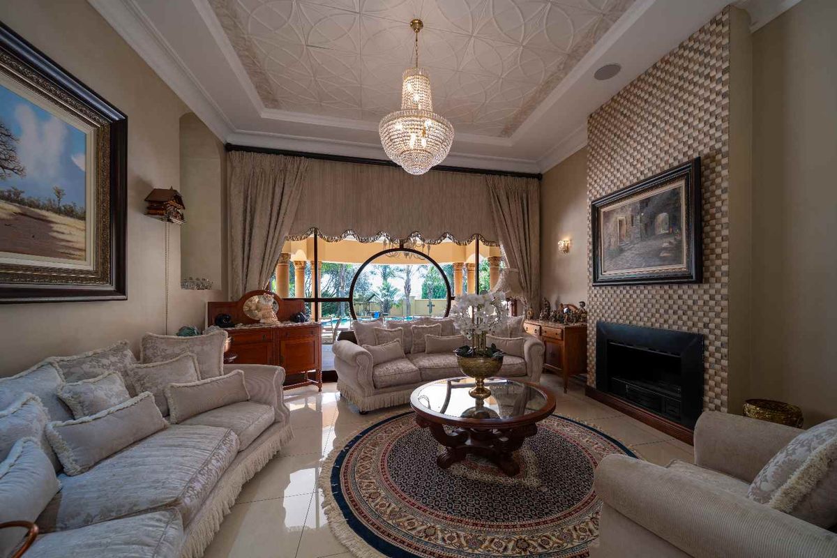 Elegant living room featuring a built-in fireplace, decorative ceiling detail, and large arched windows providing natural light and views of the outdoor area.