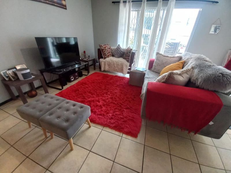 A living room featuring tiled flooring and a sliding glass door with an integrated security gate, providing access to the exterior.