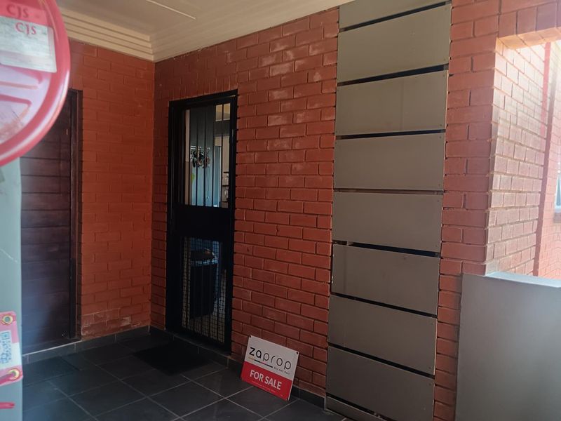 Entrance area featuring exposed brick walls, tiled flooring, and a secure metal gate.