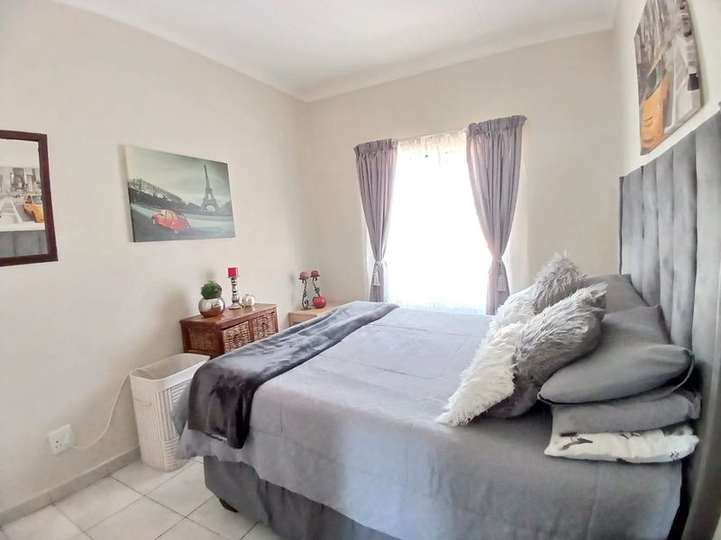 A well-lit bedroom featuring neutral wall tones and tiled flooring, providing a comfortable and functional living space.