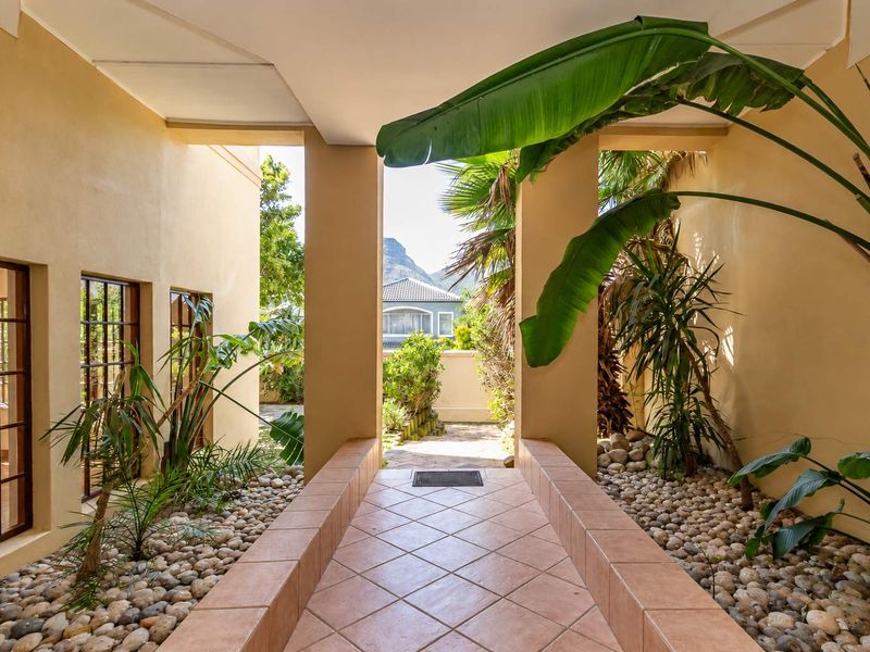 A covered entrance walkway featuring tiled flooring and decorative pebble garden beds, leading towards the front of the property.