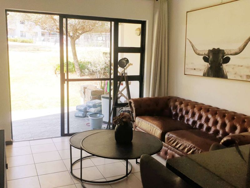 A bright living room featuring tiled flooring and a large sliding glass door that provides direct access to the outdoor patio area.