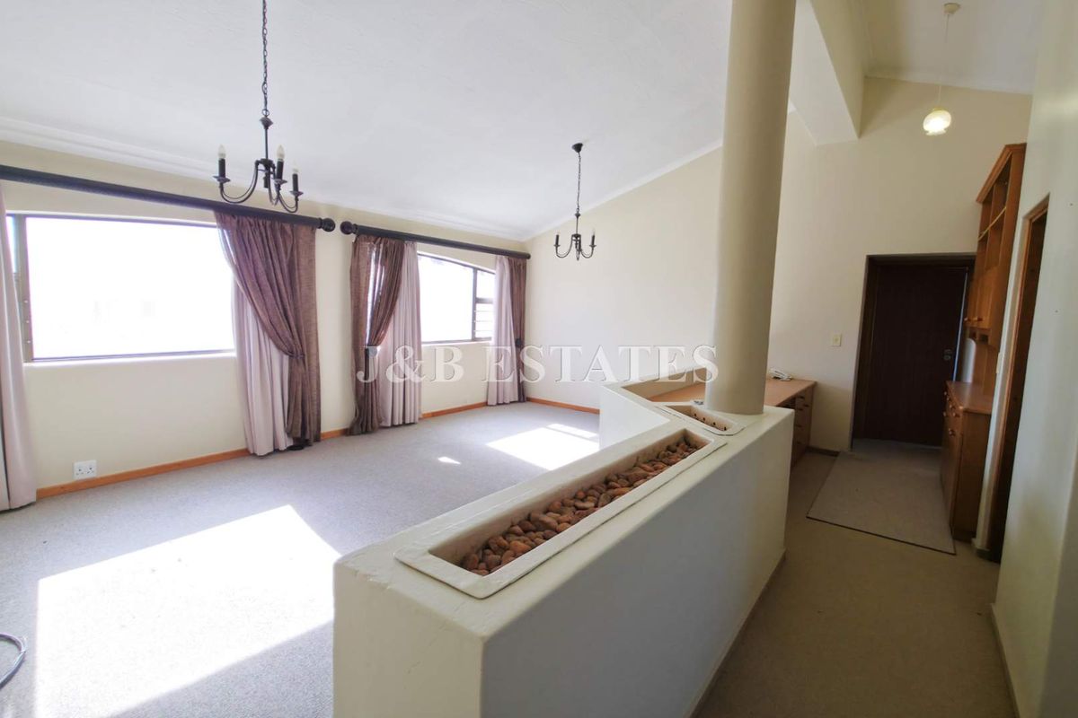 Spacious living area featuring high ceilings, a central structural pillar with a built-in planter, and large windows allowing for ample natural light.