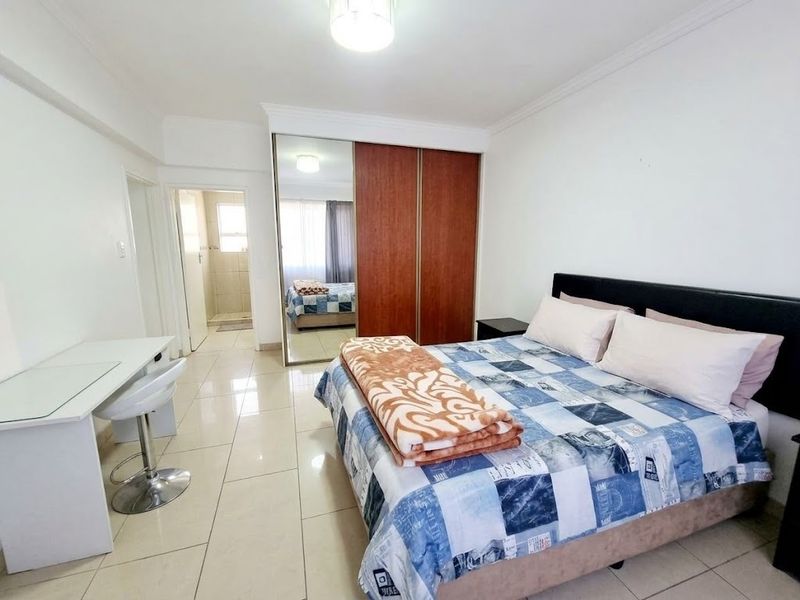 A bedroom featuring tiled flooring, coved ceilings, and a built-in wardrobe with mirrored sliding doors.
