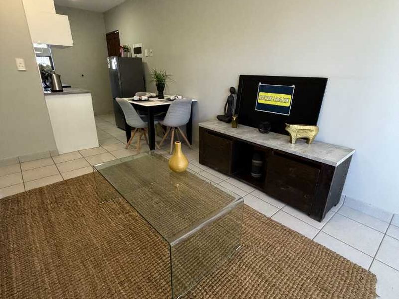 Open plan living area featuring tiled flooring and a compact kitchen space with built-in cabinetry.