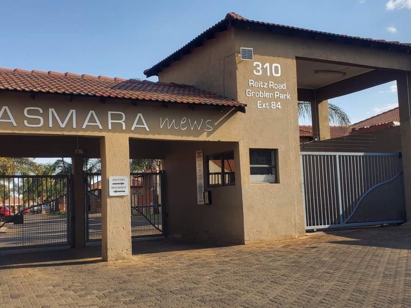 The entrance to Asmara Mews complex, featuring a secure gated access point with paved driveway and established perimeter structure.