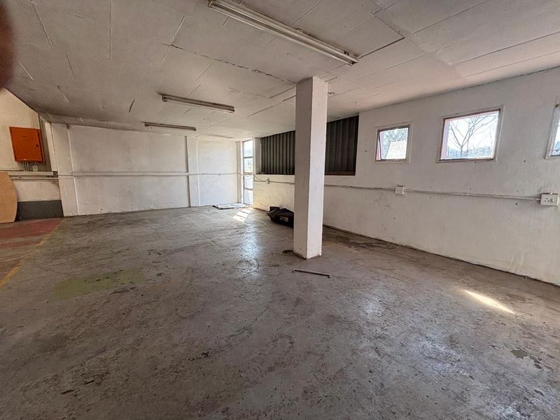 An empty industrial utility space featuring concrete flooring, exposed structural columns, and surface-mounted electrical conduits, suitable for storage or workshop use.