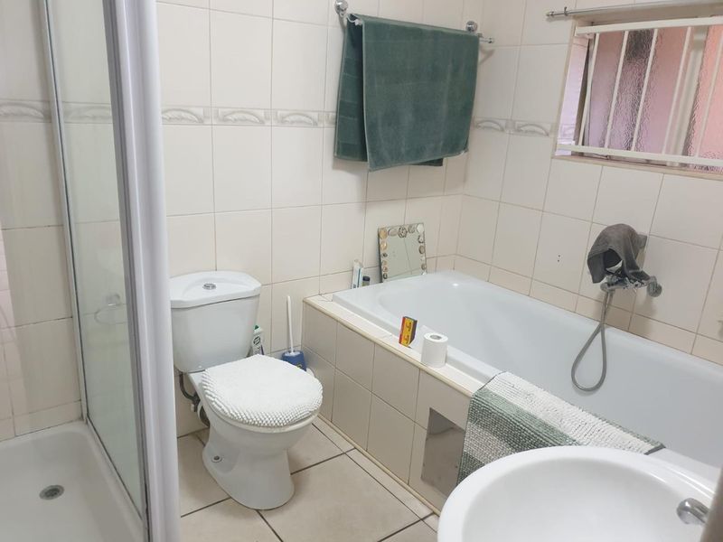 A functional bathroom featuring a separate shower enclosure, bathtub, toilet, and tiled finishes throughout.