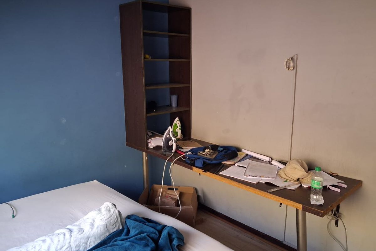 A bedroom featuring a built-in desk and shelving unit with laminate flooring and two-tone painted walls.