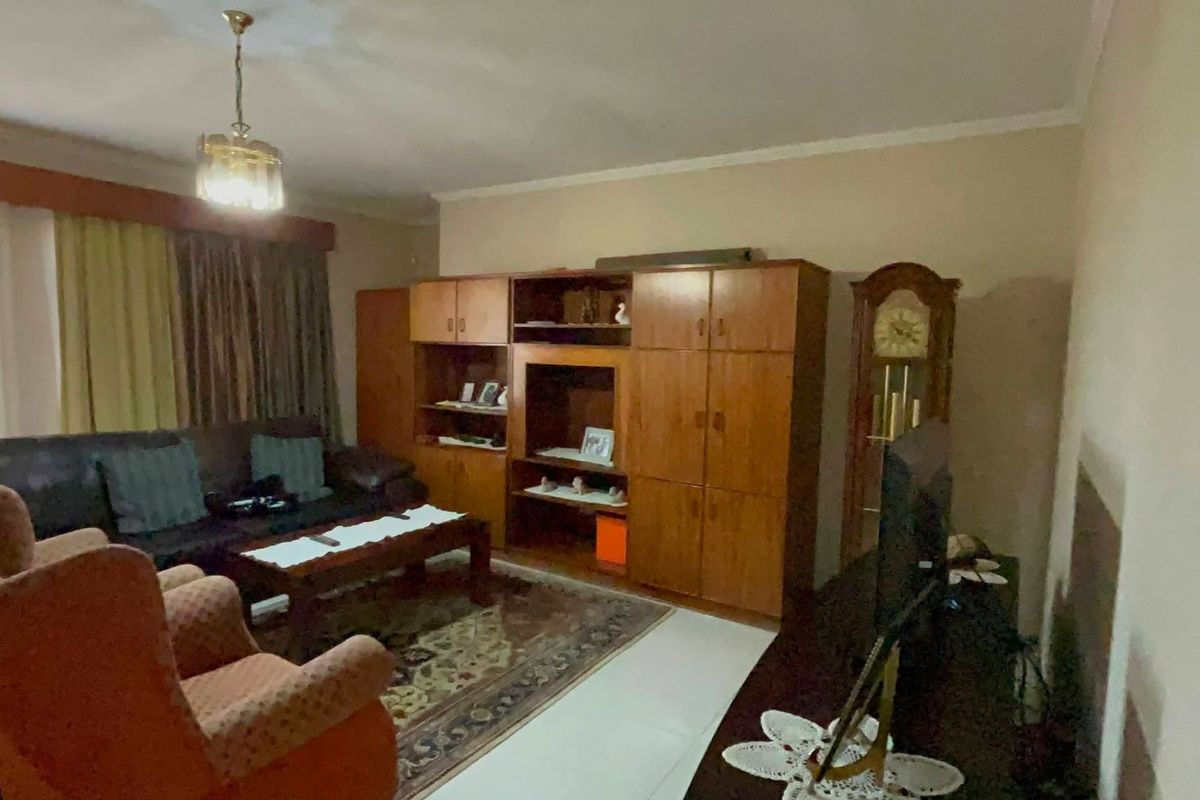 A traditional living room featuring built-in wooden cabinetry and tiled flooring, offering a functional space with potential for modern updates.