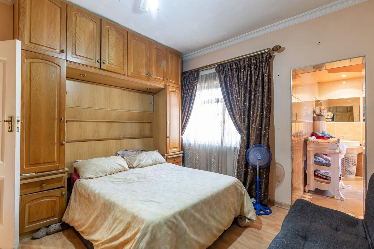A bedroom featuring built-in wooden cabinetry and an en-suite bathroom with tiled finishes.