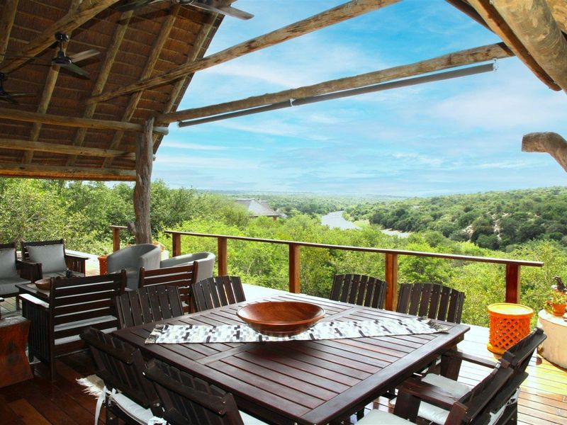Spacious covered outdoor patio featuring a thatched roof, timber decking, and panoramic views of the surrounding landscape and river.