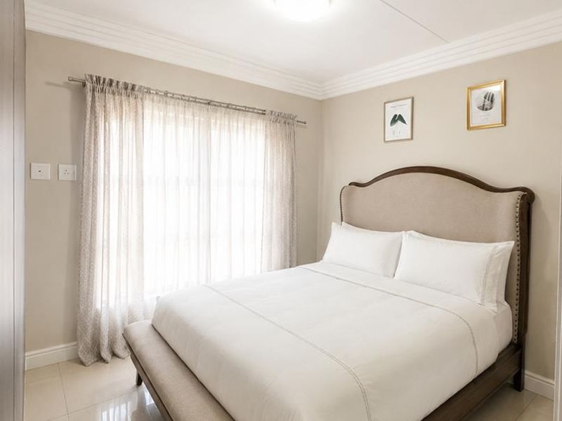 A well-maintained bedroom featuring neutral wall tones, polished tiled flooring, and classic ceiling cornice detailing.