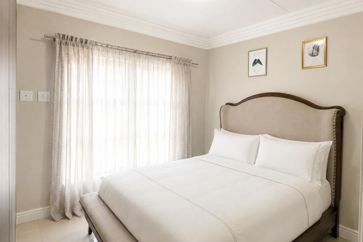 A well-maintained bedroom featuring neutral wall tones, polished tiled flooring, and classic ceiling cornice detailing.