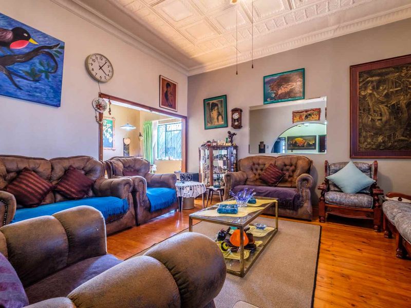 Spacious living room featuring traditional pressed metal ceilings, warm timber flooring, and an open archway leading to an adjacent room.