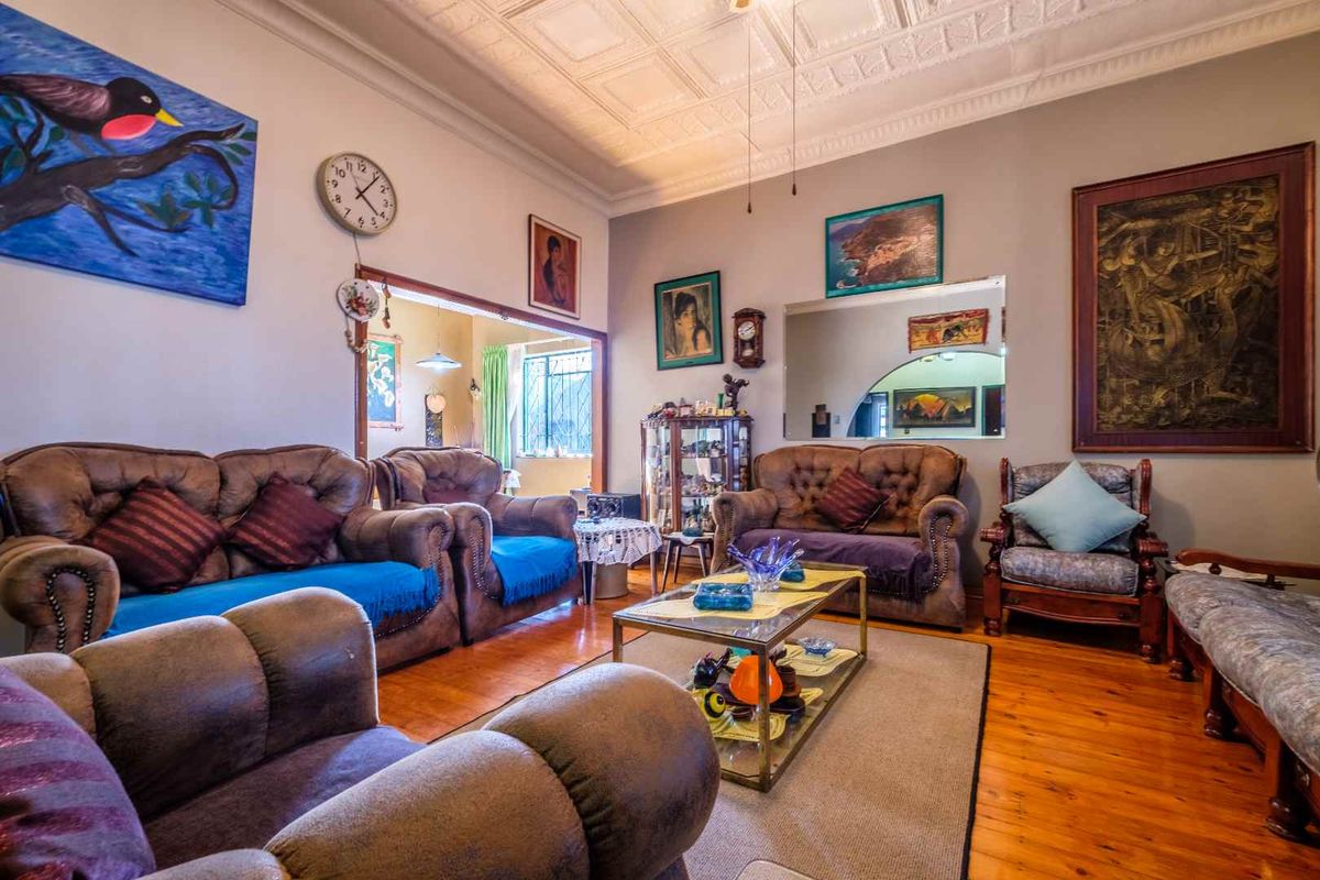 Spacious living room featuring traditional pressed metal ceilings, warm timber flooring, and an open archway leading to an adjacent room.
