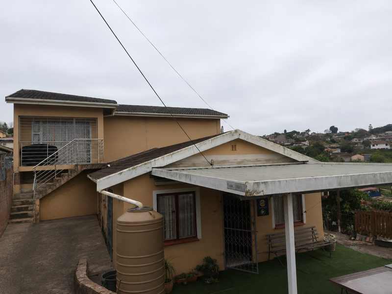 Rear view of the property featuring a covered patio area, external staircase leading to an upper level, and a water tank installation.