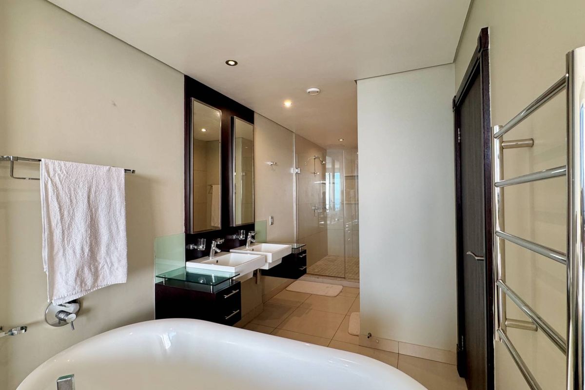 Modern bathroom featuring a double vanity, freestanding bathtub, and a separate walk-in shower with glass enclosure and heated towel rail.