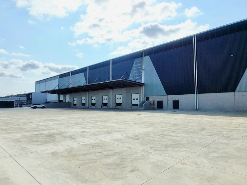 Large industrial warehouse facility featuring multiple loading docks, a spacious concrete yard, and modern metal cladding exterior.