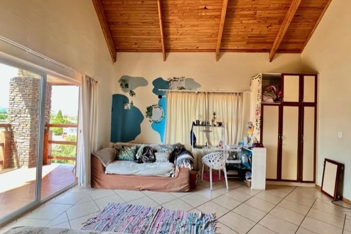 Spacious bedroom featuring high vaulted timber ceilings, tiled flooring, built-in cabinetry, and large sliding glass doors opening onto a private balcony.