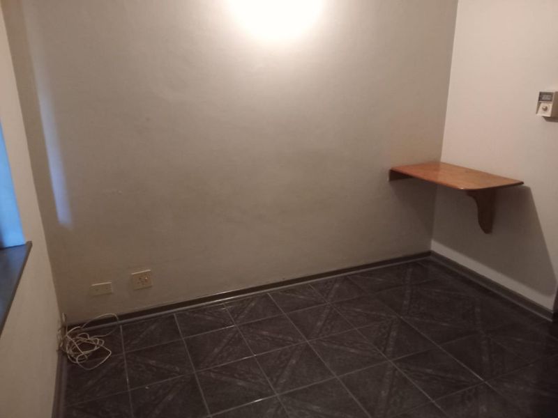An empty bedroom featuring dark tiled flooring and a built-in wall-mounted wooden desk.