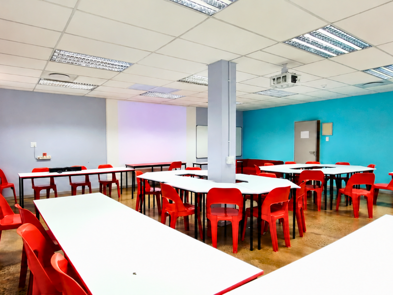 A functional office or training room featuring a suspended ceiling, recessed lighting, and a central structural column, suitable for collaborative work or educational purposes.