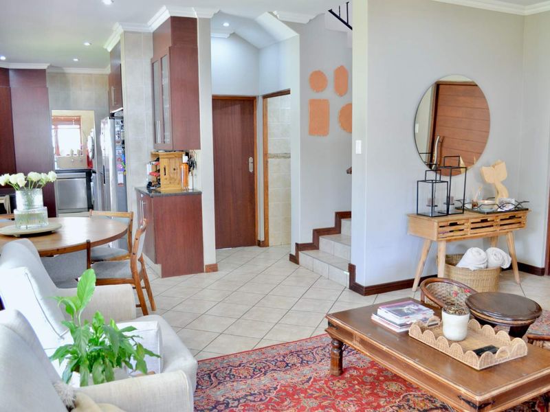 Open-plan living and dining area featuring tiled flooring, recessed lighting, and direct access to a scullery and staircase.