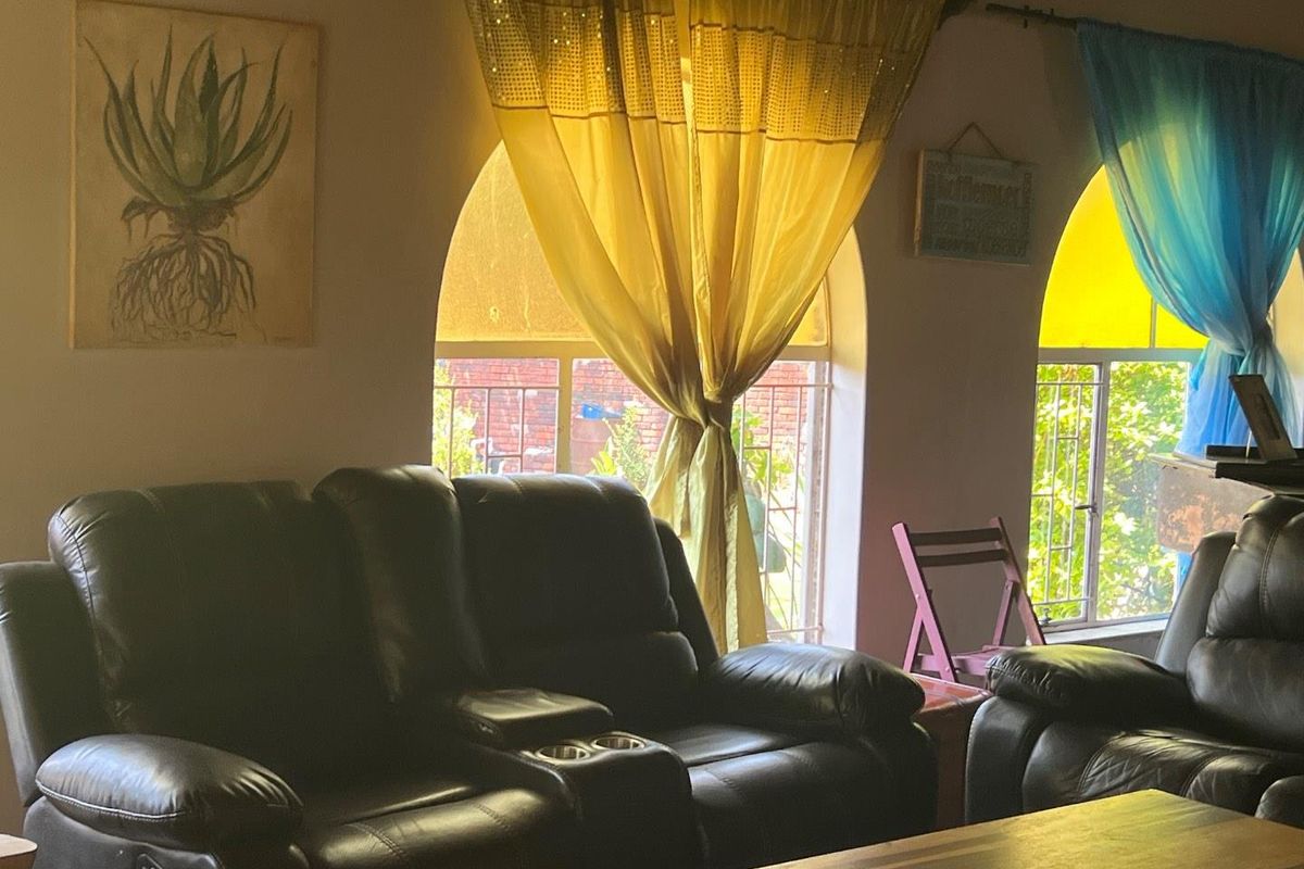 A living room featuring distinctive arched windows with security bars, providing natural light and a view of the exterior.