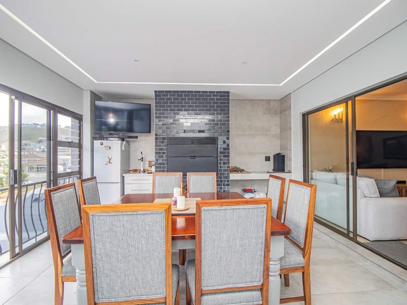 Enclosed patio area featuring a built-in braai, modern subway tile backsplash, and large sliding glass doors providing ample natural light.