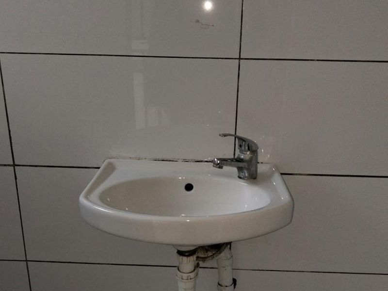 A simple wall-mounted bathroom basin featuring a chrome mixer tap set against white ceramic wall tiles.