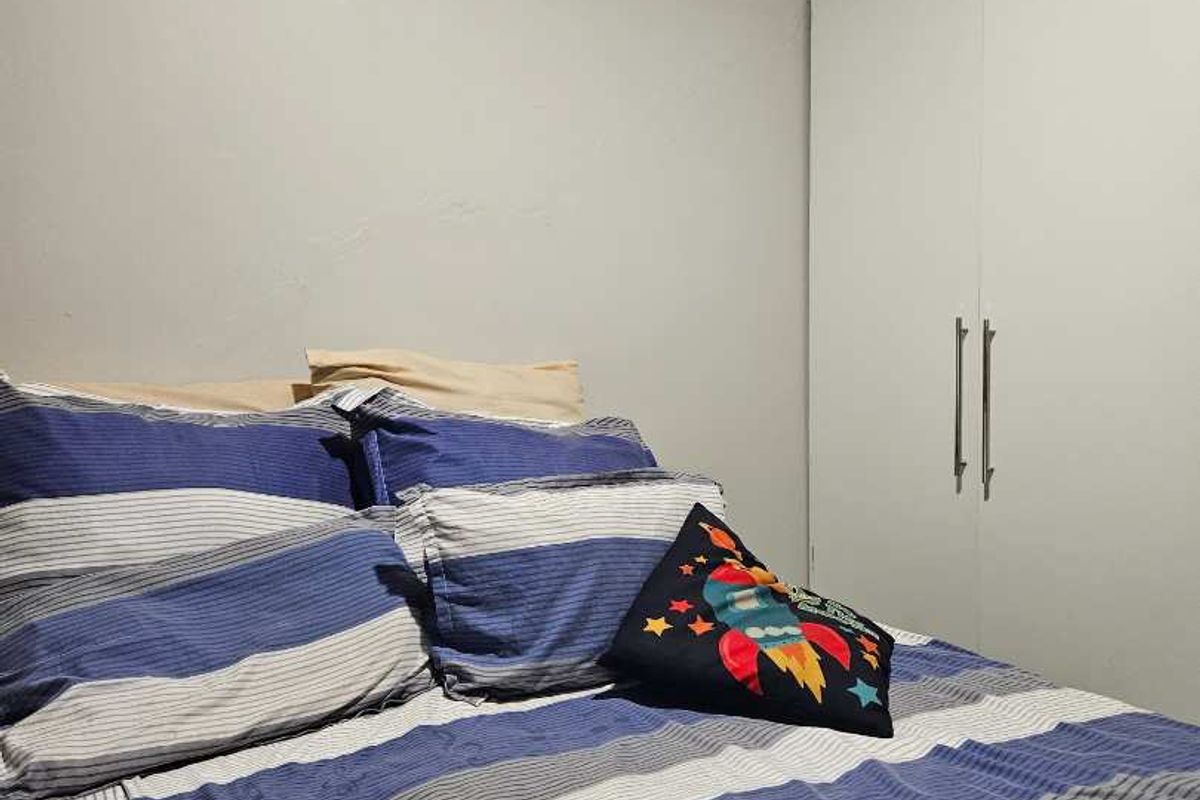 A bedroom featuring a built-in wardrobe with white doors, providing functional storage space within the room.