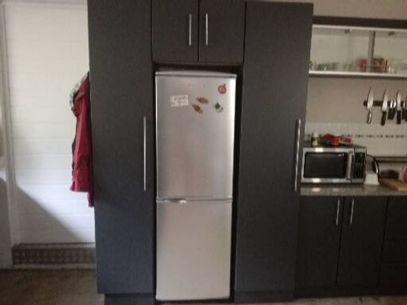 A functional kitchen area featuring dark built-in cabinetry, granite countertops, and integrated appliance storage.