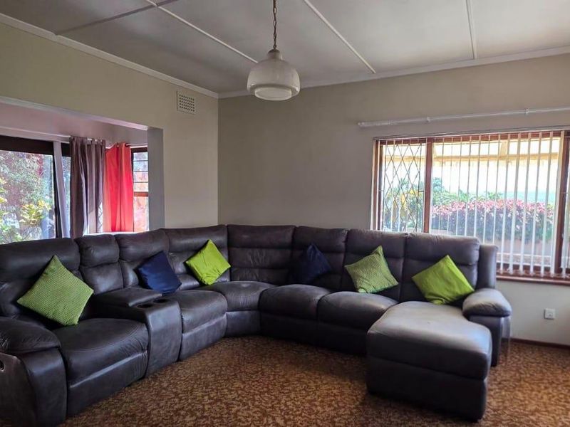 Spacious living room featuring large windows with security bars, sliding door access to the exterior, and neutral wall finishes.