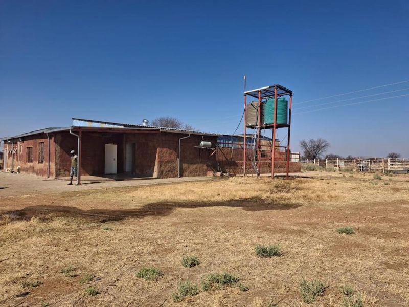Rear view of the small holding dwelling featuring a covered patio area and an elevated water storage tank structure.