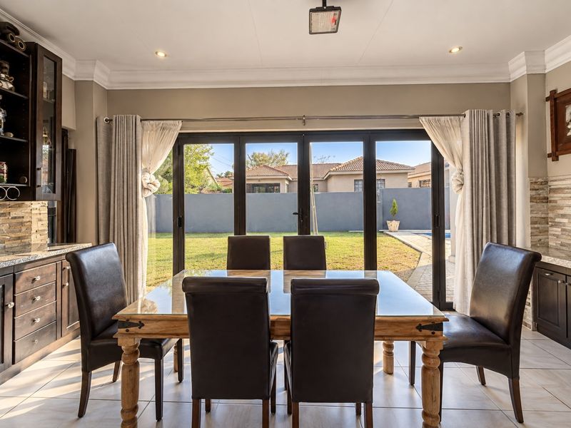 Elegant dining area featuring tiled floors, built-in cabinetry, and large bi-fold doors providing seamless access to the rear garden and pool area.