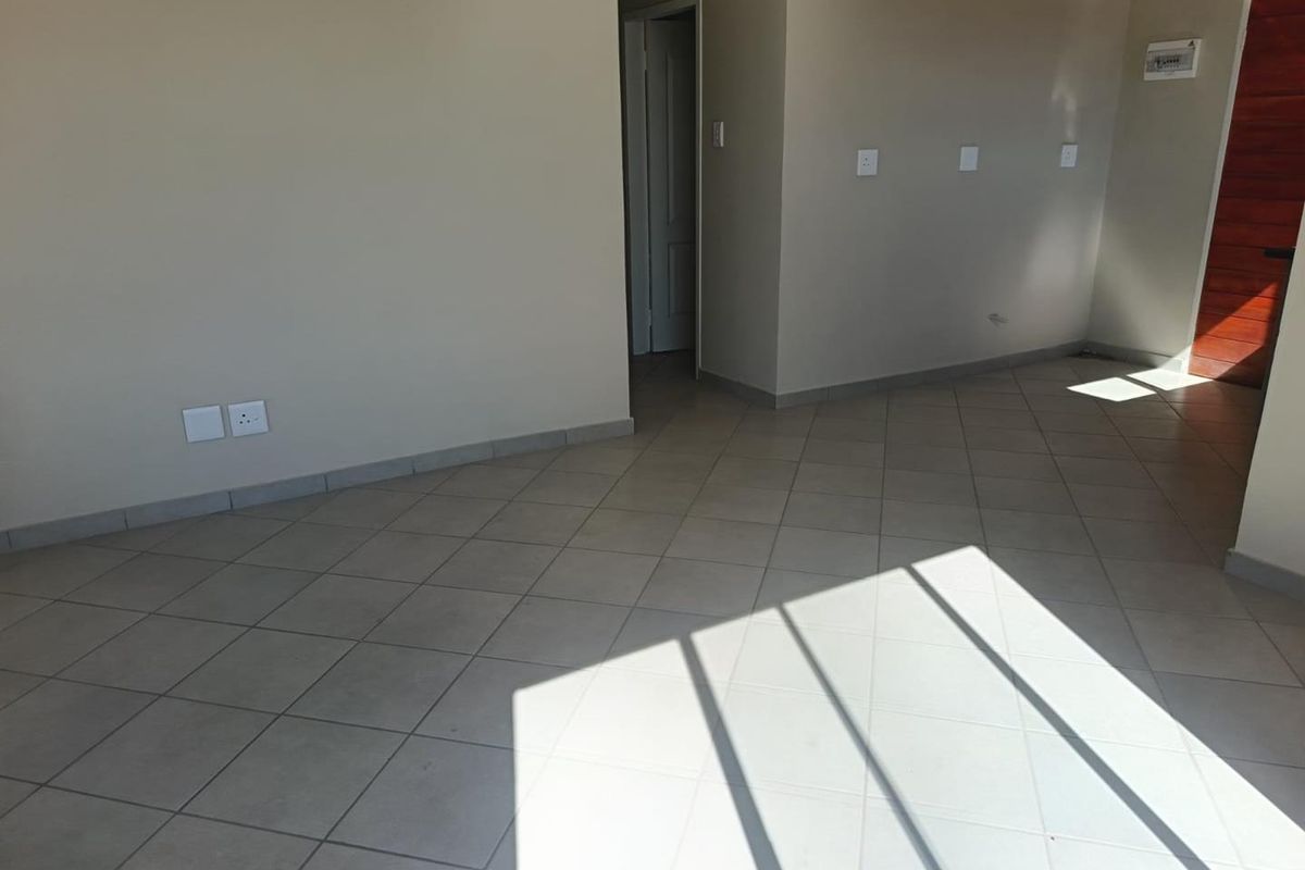A bright, empty living area featuring neutral tiled flooring and clean wall finishes, providing a versatile blank canvas for interior design.