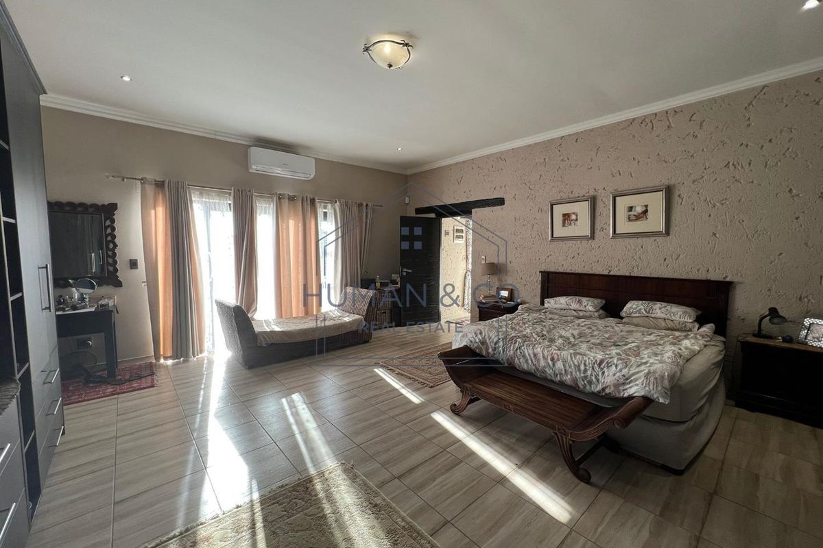 Spacious bedroom featuring tiled flooring, a textured accent wall, and a wall-mounted air conditioning unit with direct access to the exterior.