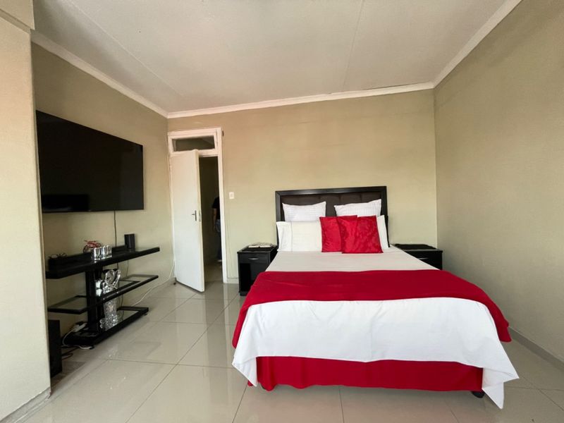 A well-maintained bedroom featuring neutral wall tones, tiled flooring, and a coved ceiling, providing a clean and functional living space.