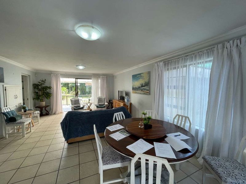 An open-plan living and dining area featuring tiled flooring, coved cornicing, and large sliding glass doors that provide access to the outdoor patio space.