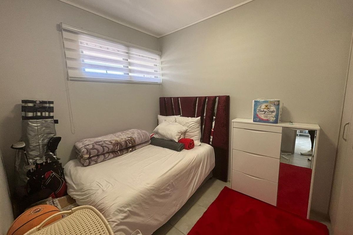 A compact bedroom featuring tiled flooring, a built-in cupboard, and a horizontal window with fitted blinds.