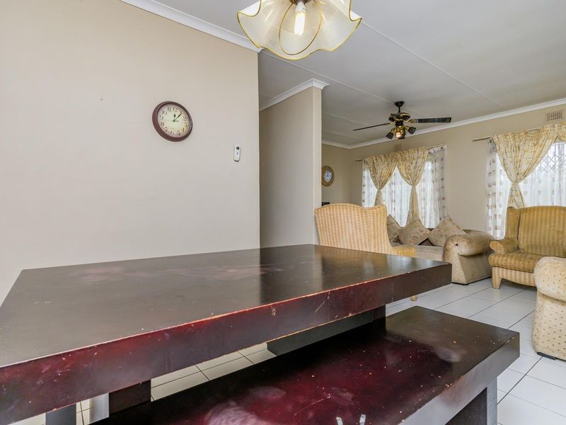 Open plan living and dining area featuring tiled flooring, coved cornicing, and a ceiling fan, offering a functional layout for family living.