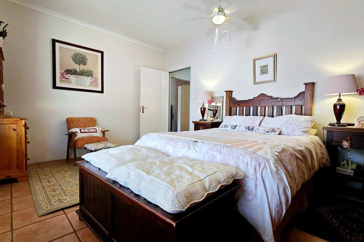 A well-maintained bedroom featuring tiled flooring, a ceiling fan, and neutral wall finishes, providing a comfortable and functional living space.