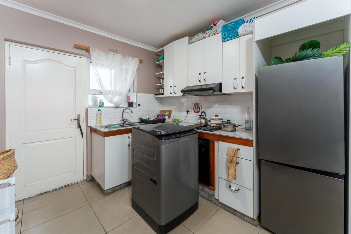 Compact kitchen featuring white cabinetry, tiled backsplash, built-in oven, extractor fan, and tiled flooring, providing a functional workspace.