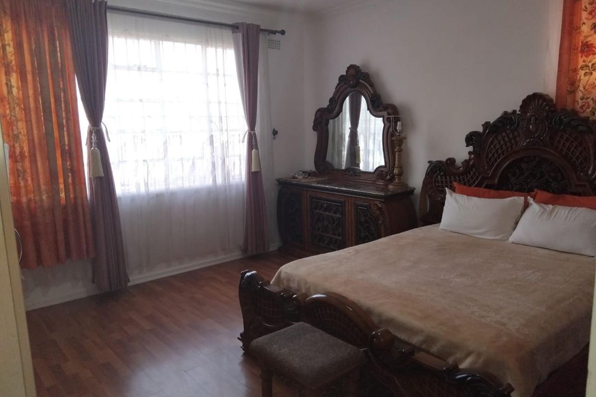 A bedroom featuring laminate wood flooring and a large window with natural light.