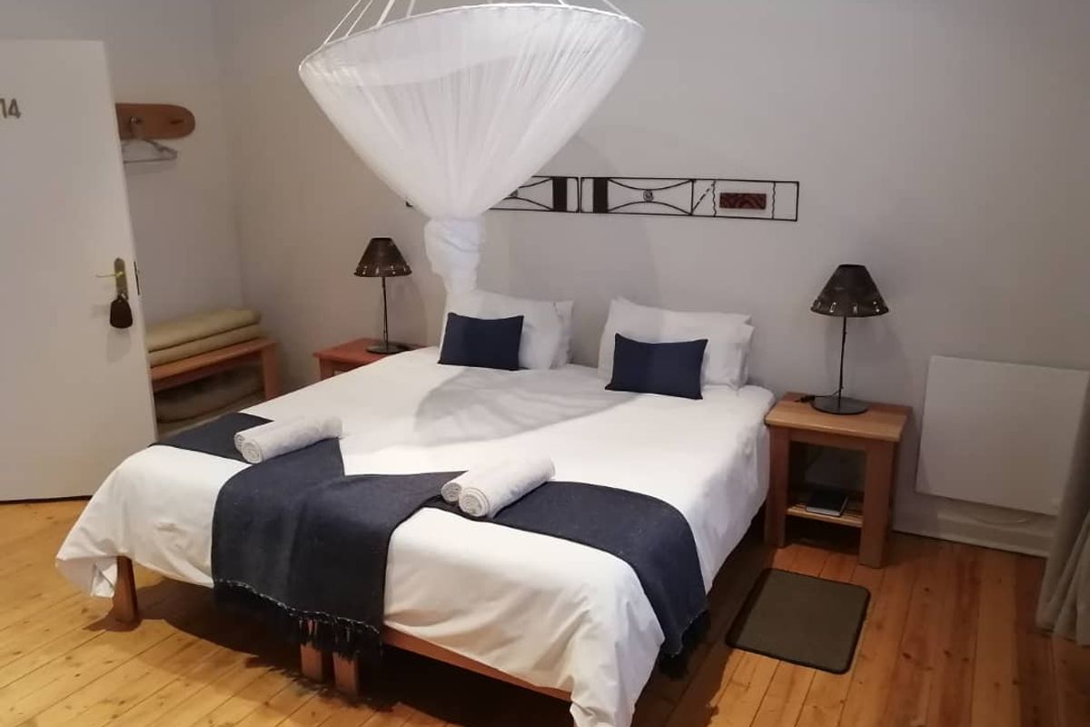 A hotel bedroom featuring polished wooden flooring and a wall-mounted electric heater.
