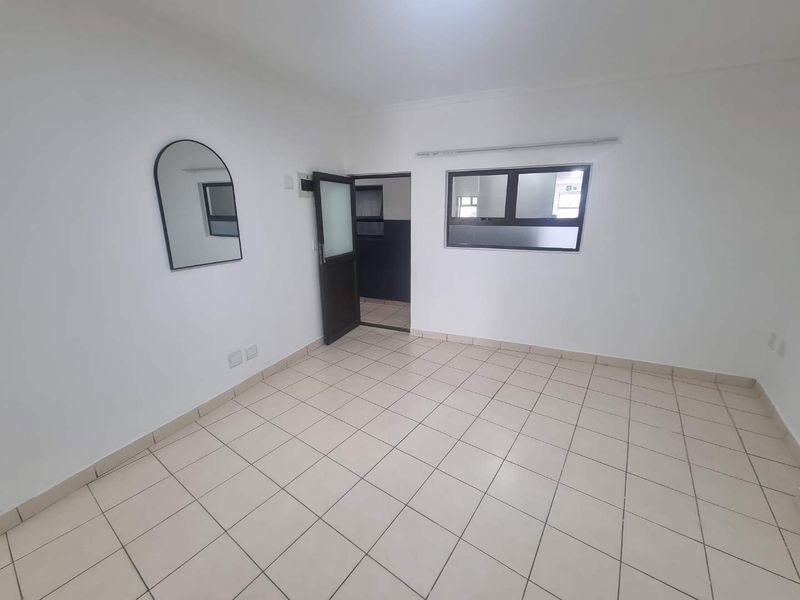 A bright, empty living area featuring neutral tiled flooring and clean white walls, providing a versatile blank canvas for interior design.