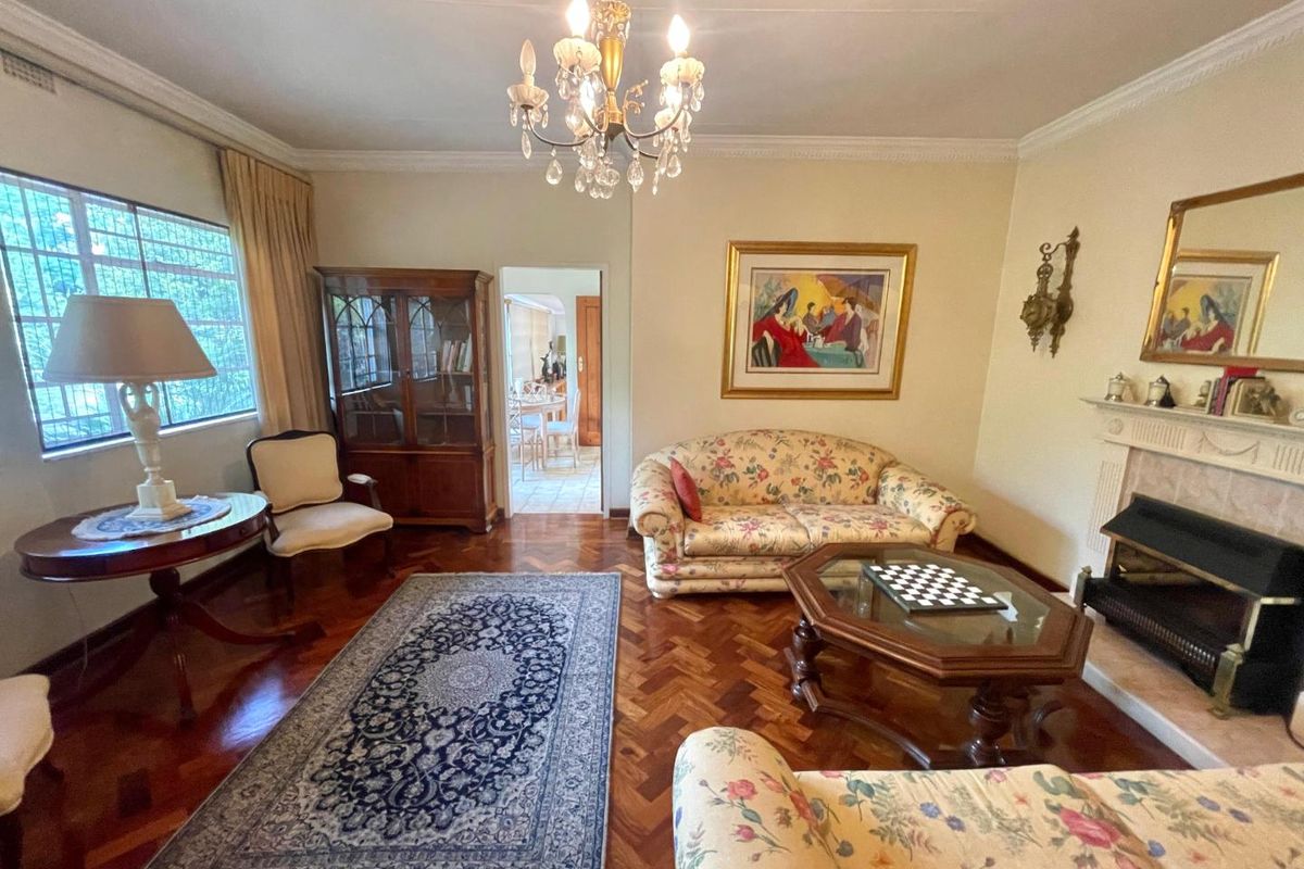 A classic living room featuring polished herringbone parquet flooring, a traditional fireplace, and decorative crown molding.